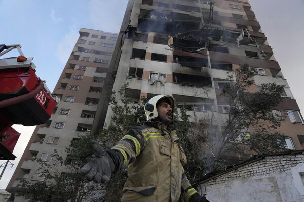 Пожарный на фоне дома, пострадавшего во время авиаударов на севере Тегерана, Иран, 13 июня 2025 года - Sputnik Латвия